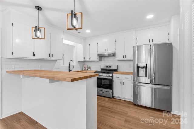 kitchen with wooden counters, appliances with stainless steel finishes, white cabinetry, and hanging light fixtures