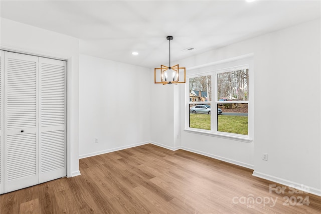 unfurnished dining area featuring light wood-type flooring and an inviting chandelier