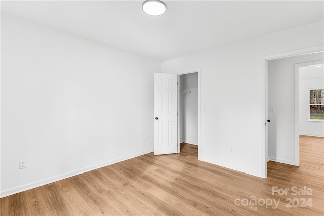 unfurnished bedroom with a walk in closet, light hardwood / wood-style floors, and a closet