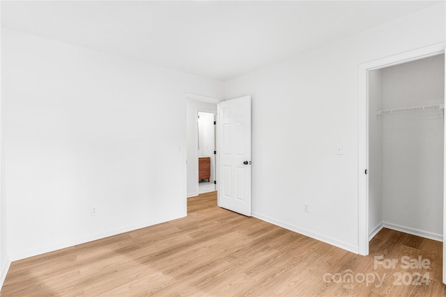 unfurnished bedroom with light wood-type flooring and a closet