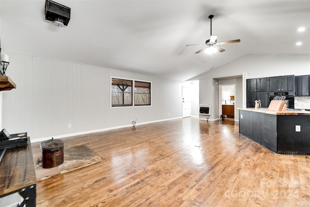 living room with heating unit, hardwood / wood-style flooring, vaulted ceiling, and ceiling fan