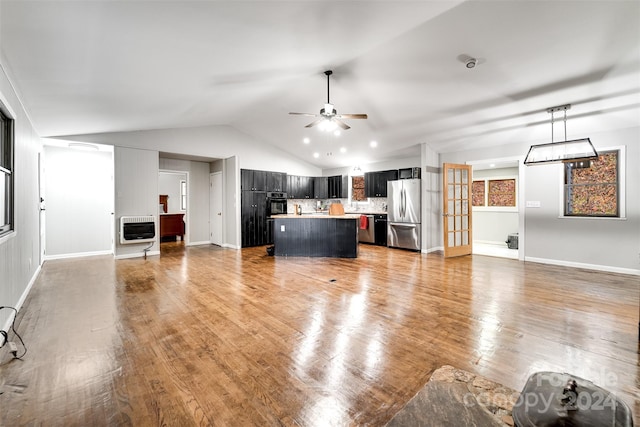 unfurnished living room featuring hardwood / wood-style flooring, ceiling fan, vaulted ceiling, and heating unit