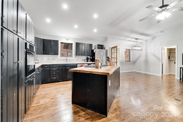 kitchen with stainless steel fridge, ceiling fan, decorative light fixtures, a center island, and black oven