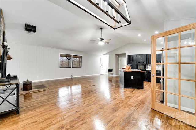 living room with hardwood / wood-style floors, heating unit, ceiling fan, and lofted ceiling