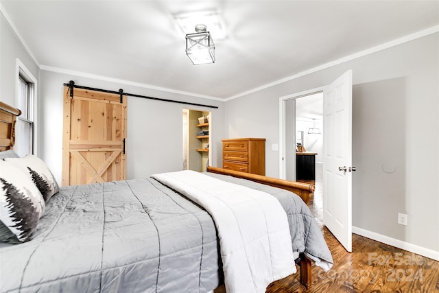 bedroom with hardwood / wood-style floors, crown molding, a barn door, a spacious closet, and a closet