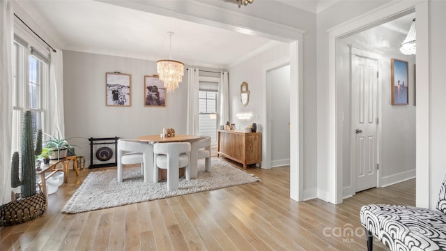 dining area featuring hardwood / wood-style floors, ornamental molding, and an inviting chandelier