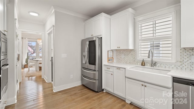 kitchen featuring white cabinetry, sink, stainless steel appliances, light hardwood / wood-style floors, and decorative backsplash