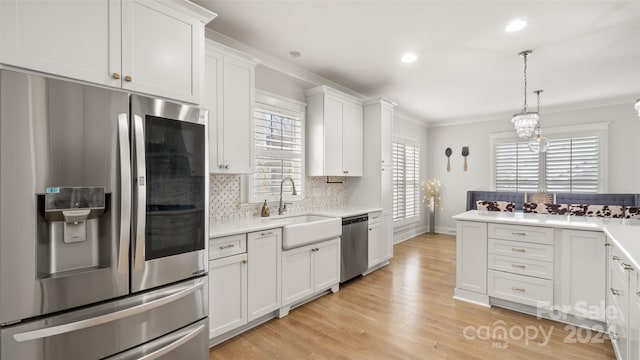 kitchen featuring appliances with stainless steel finishes, light wood-type flooring, tasteful backsplash, ornamental molding, and white cabinets