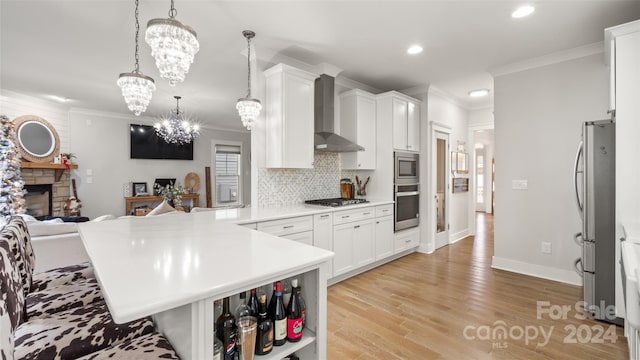 kitchen featuring pendant lighting, an inviting chandelier, wall chimney exhaust hood, a fireplace, and stainless steel appliances