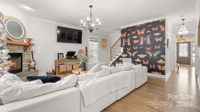 living room with a fireplace, light wood-type flooring, crown molding, and a notable chandelier