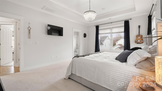 carpeted bedroom featuring a tray ceiling and an inviting chandelier