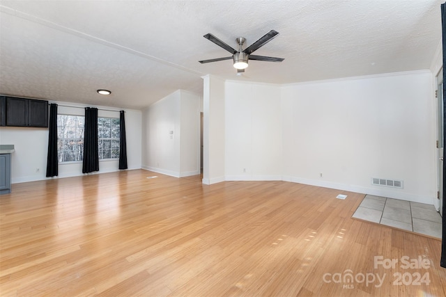 unfurnished living room featuring ceiling fan, ornamental molding, a textured ceiling, and light wood-type flooring