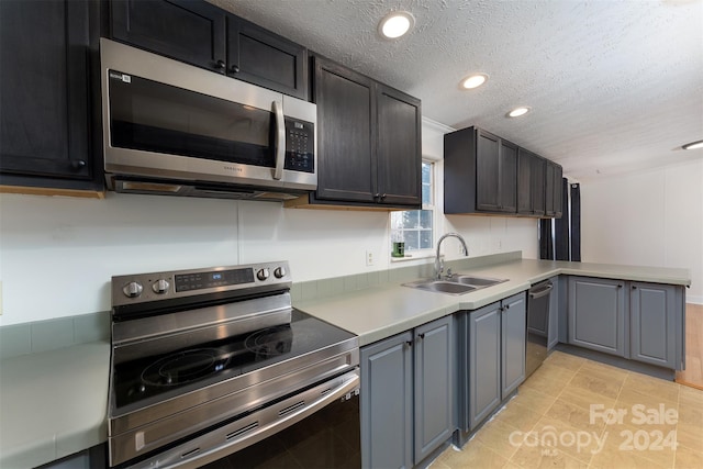 kitchen featuring sink, light tile patterned floors, stainless steel appliances, and a textured ceiling