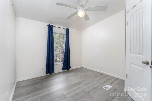 spare room with ceiling fan, light hardwood / wood-style floors, and a textured ceiling