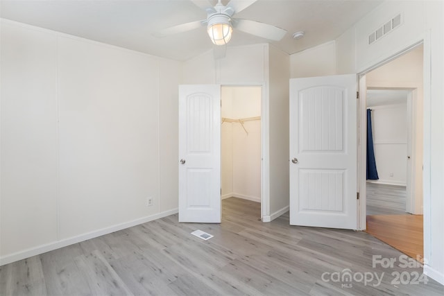 unfurnished bedroom featuring ceiling fan, a spacious closet, and light hardwood / wood-style flooring