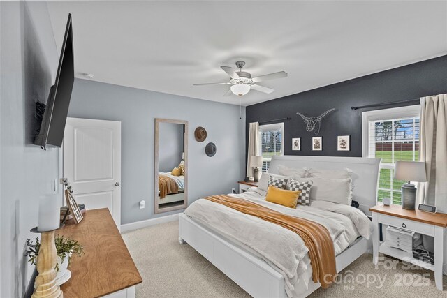 bedroom featuring multiple windows, ceiling fan, and light colored carpet