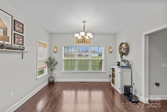 dining space with dark hardwood / wood-style floors and a notable chandelier