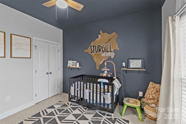 carpeted bedroom featuring ceiling fan, a closet, and a nursery area