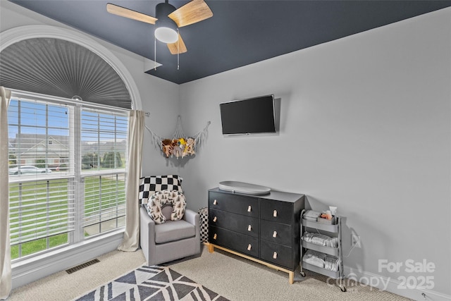 living area featuring ceiling fan, plenty of natural light, and light carpet