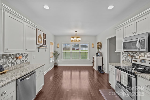 kitchen with appliances with stainless steel finishes, backsplash, an inviting chandelier, and white cabinetry