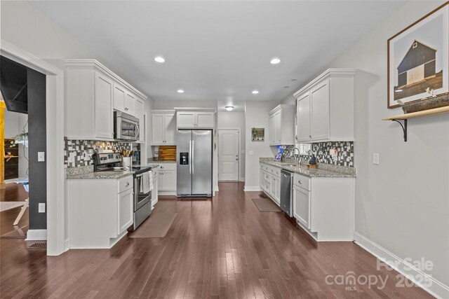 kitchen featuring light stone countertops, white cabinetry, sink, dark wood-type flooring, and stainless steel appliances