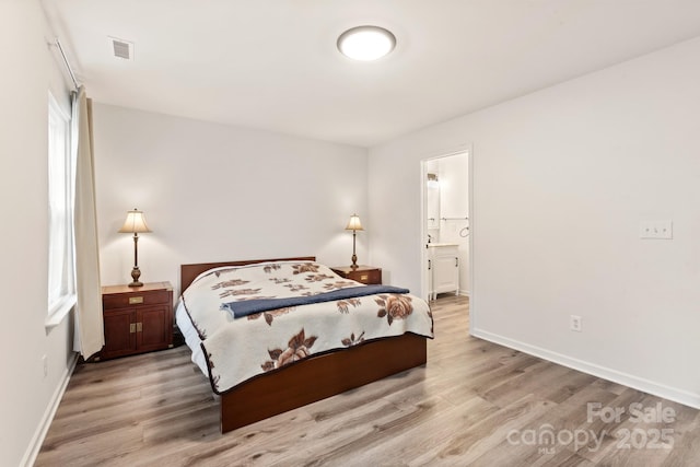 bedroom featuring connected bathroom and light wood-type flooring