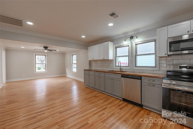 kitchen with sink, white cabinets, stainless steel appliances, and light hardwood / wood-style flooring