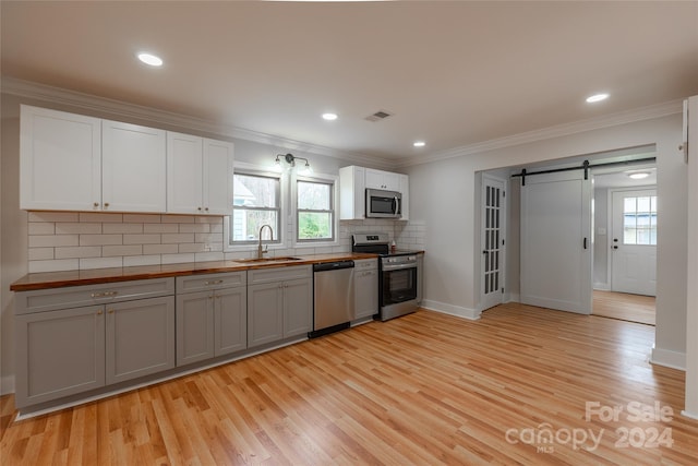 kitchen featuring appliances with stainless steel finishes, a barn door, gray cabinetry, and a healthy amount of sunlight