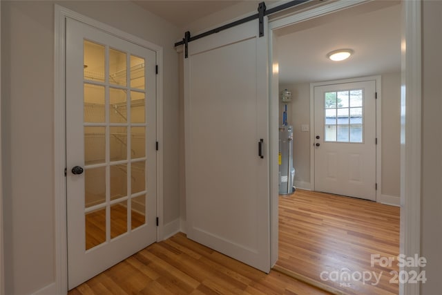 entryway featuring a barn door, light wood-type flooring, and water heater