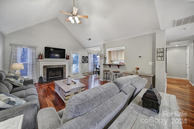 living room with a tile fireplace, high vaulted ceiling, ceiling fan, and dark wood-type flooring