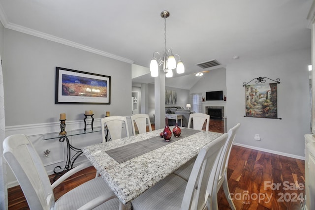 dining room with lofted ceiling, ornamental molding, dark wood-type flooring, and a chandelier