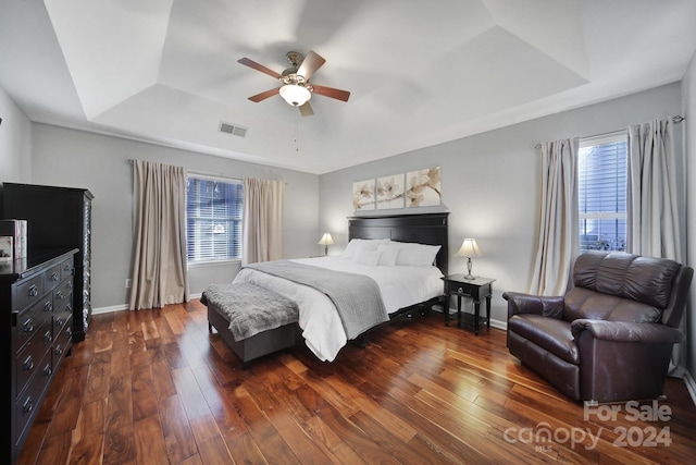 bedroom featuring a raised ceiling, ceiling fan, and dark wood-type flooring