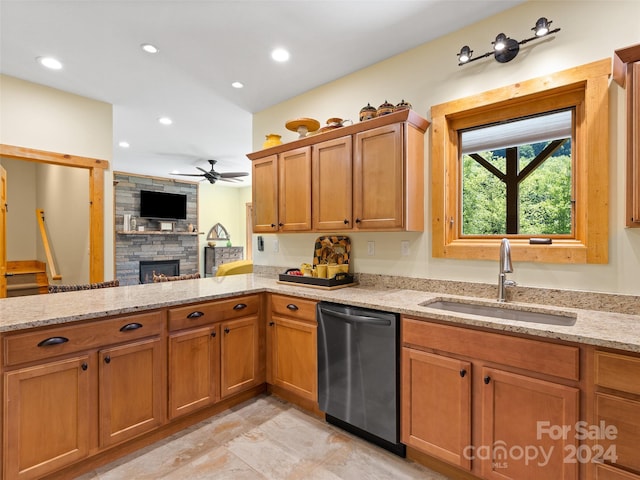 kitchen with dishwasher, sink, ceiling fan, light stone countertops, and a fireplace