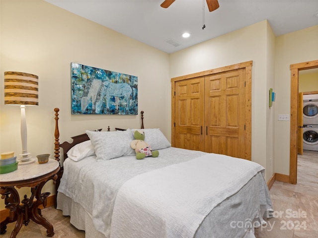 bedroom featuring ceiling fan, a closet, and stacked washer / drying machine