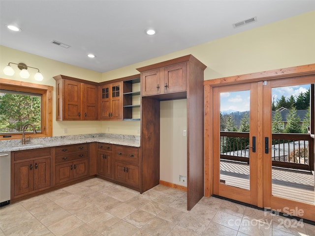 kitchen with light stone counters, sink, dishwasher, and a healthy amount of sunlight