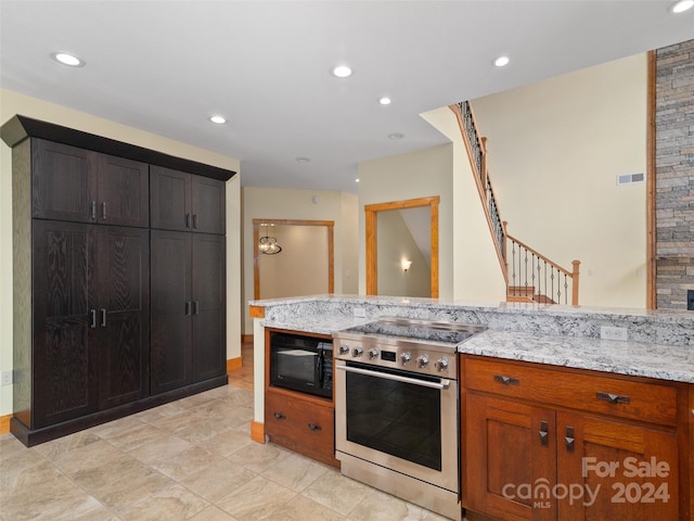 kitchen featuring stainless steel range, black microwave, and light stone counters