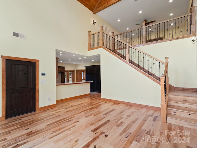 unfurnished living room featuring ceiling fan, beamed ceiling, high vaulted ceiling, and light hardwood / wood-style floors