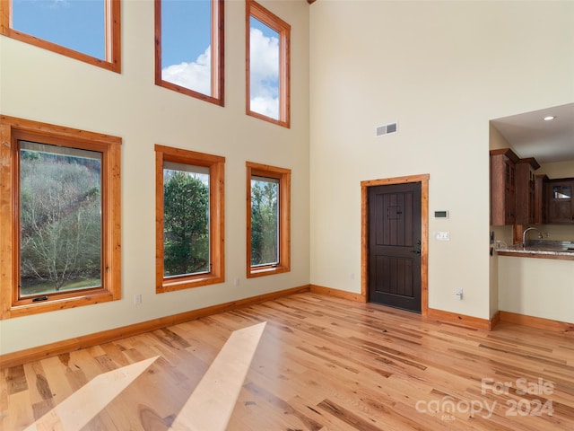 unfurnished living room featuring a high ceiling, light hardwood / wood-style flooring, and plenty of natural light