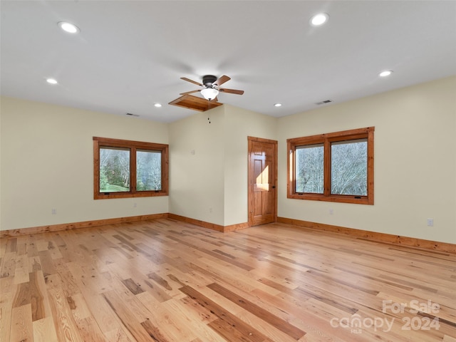 empty room featuring a wealth of natural light, ceiling fan, and light hardwood / wood-style floors