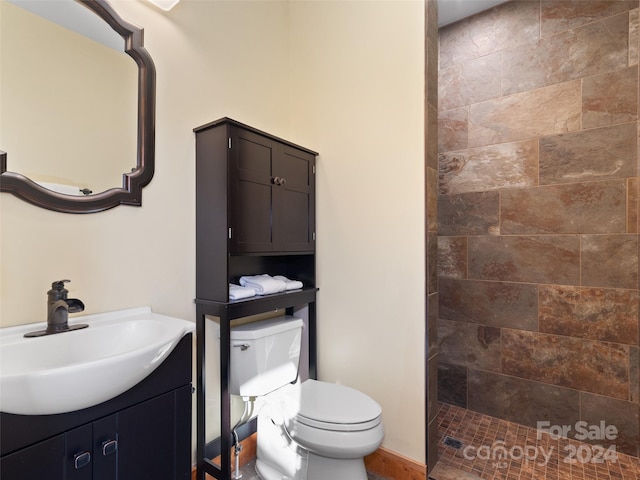 bathroom featuring a tile shower, vanity, and toilet