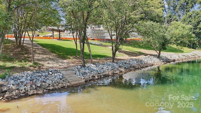 surrounding community with a water view and a lawn