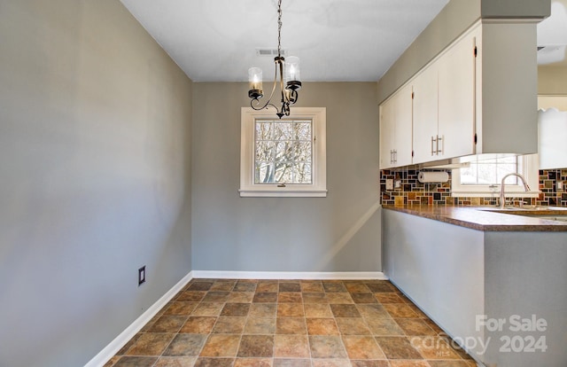 kitchen with white cabinets, pendant lighting, decorative backsplash, and a healthy amount of sunlight