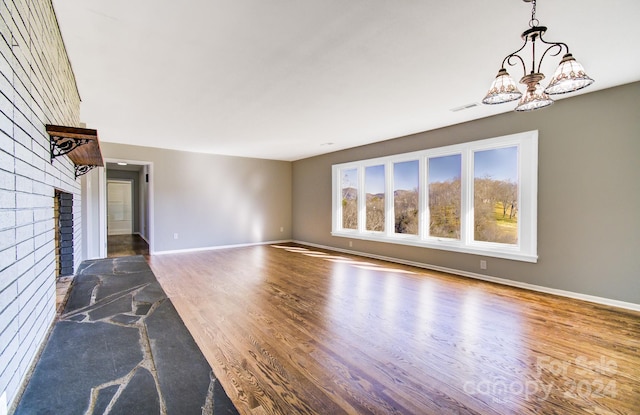 unfurnished living room featuring hardwood / wood-style floors, a fireplace, and an inviting chandelier