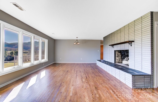 unfurnished living room featuring a notable chandelier, a large fireplace, and wood-type flooring