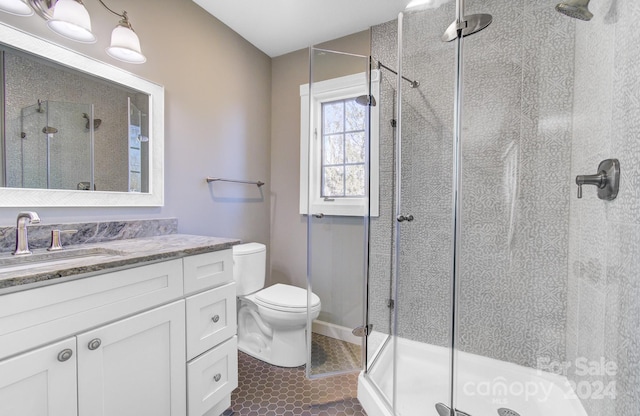 bathroom with toilet, vanity, tile patterned floors, and a shower with door