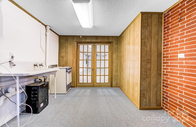 interior space featuring french doors, a textured ceiling, light colored carpet, and wooden walls