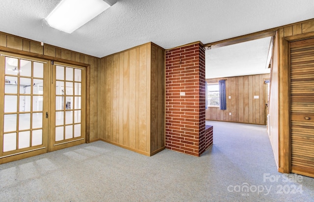 unfurnished room featuring wood walls, light colored carpet, and a textured ceiling