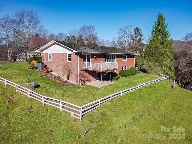 back of property featuring central AC unit, a wooden deck, a patio, and a lawn