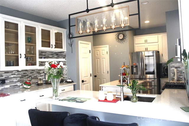 kitchen with stainless steel refrigerator with ice dispenser, decorative light fixtures, a kitchen breakfast bar, decorative backsplash, and white cabinets