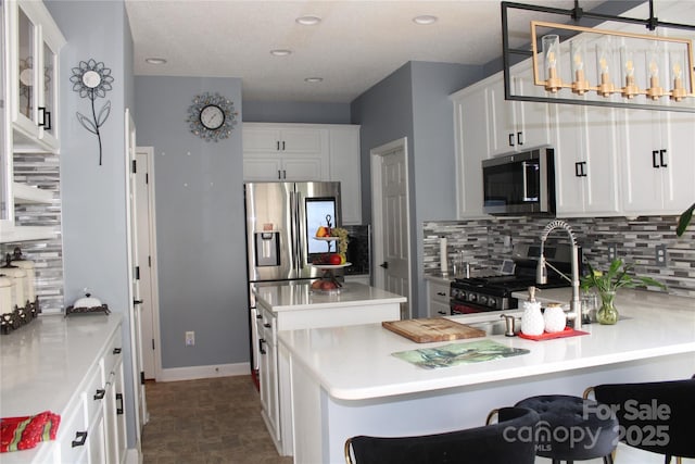 kitchen featuring a breakfast bar, appliances with stainless steel finishes, hanging light fixtures, tasteful backsplash, and white cabinets